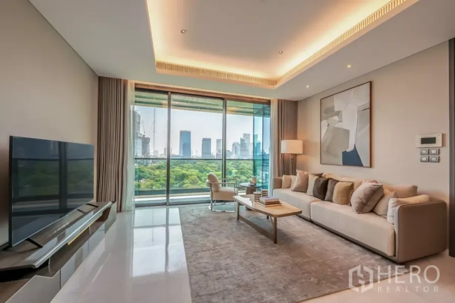 Condominium for rent or sale in Pathum Wan, Bangkok - Living room facing balcony with TV console and stunning park and city views.