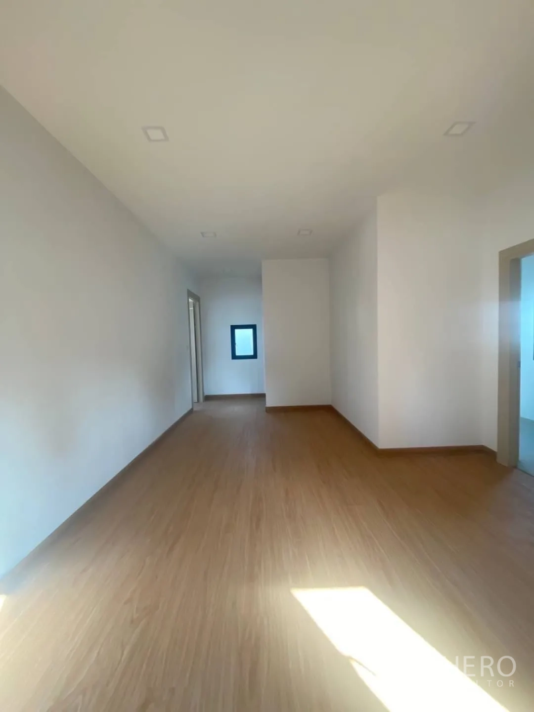 Home Office for sale - Deep open room with wood floors leading to bathrooms and a side window.