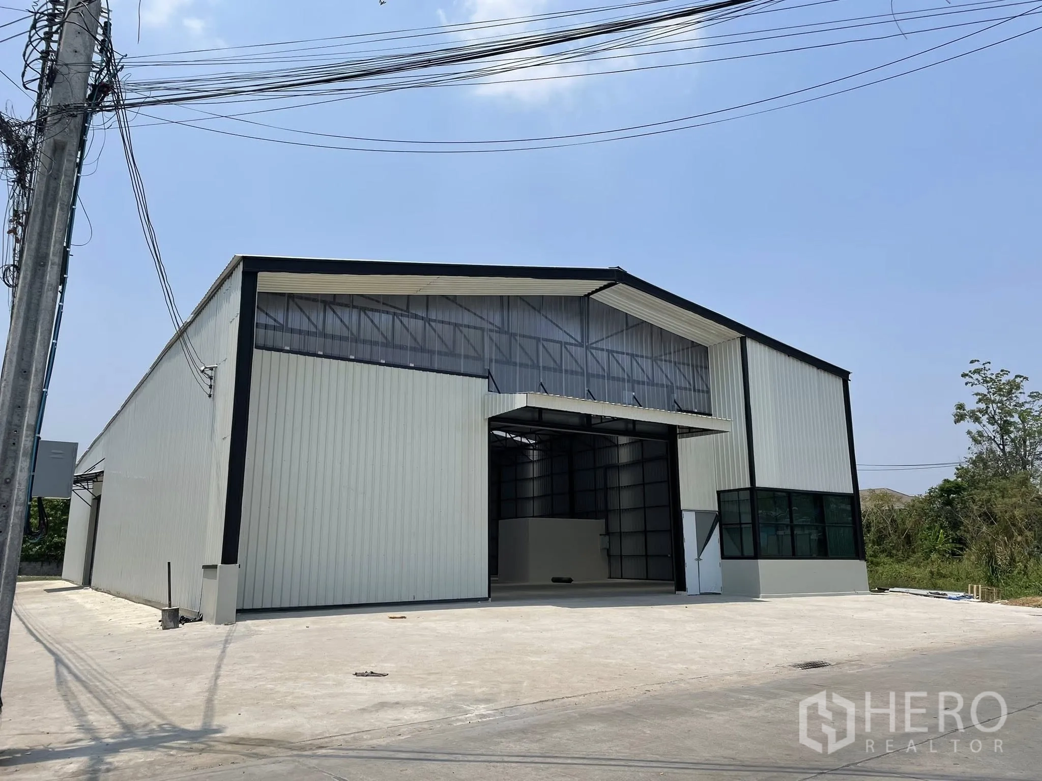 Warehouse for rent in Pak Kret, Nonthaburi - Front elevation showing a wide loading bay with canopy and a paved forecourt.