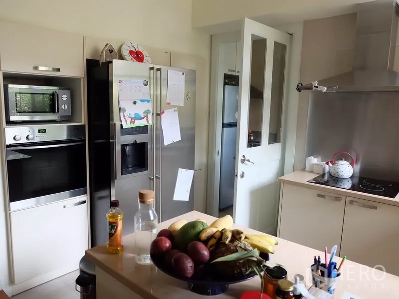 Detached House for rent in Watthana, Bangkok - Modern kitchen with built-in oven and microwave, double-door fridge, and induction cooktop.