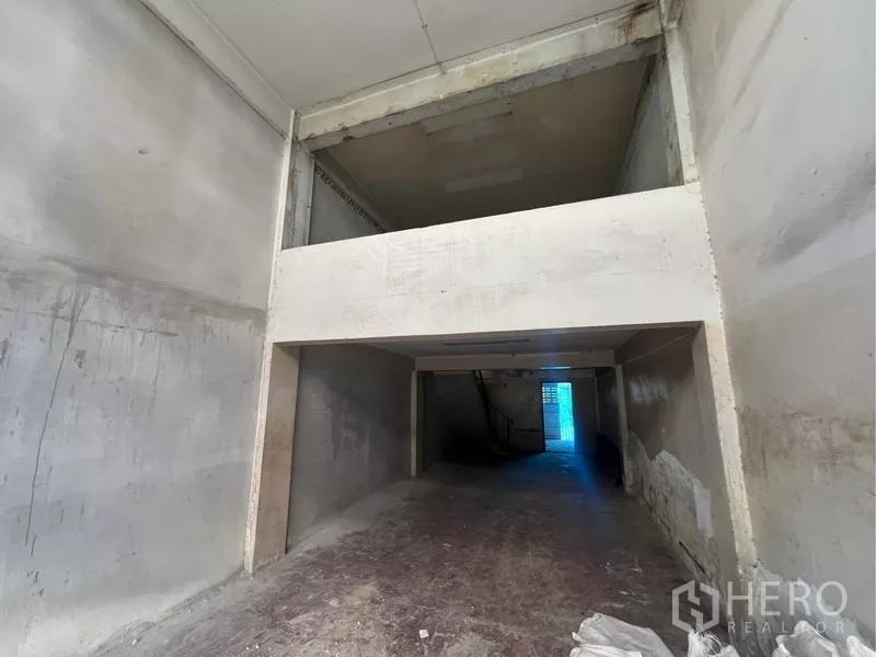 Shophouse for rent in Bangkok - Tall interior section showing a potential mezzanine level and unfinished concrete walls inside the shophouse.