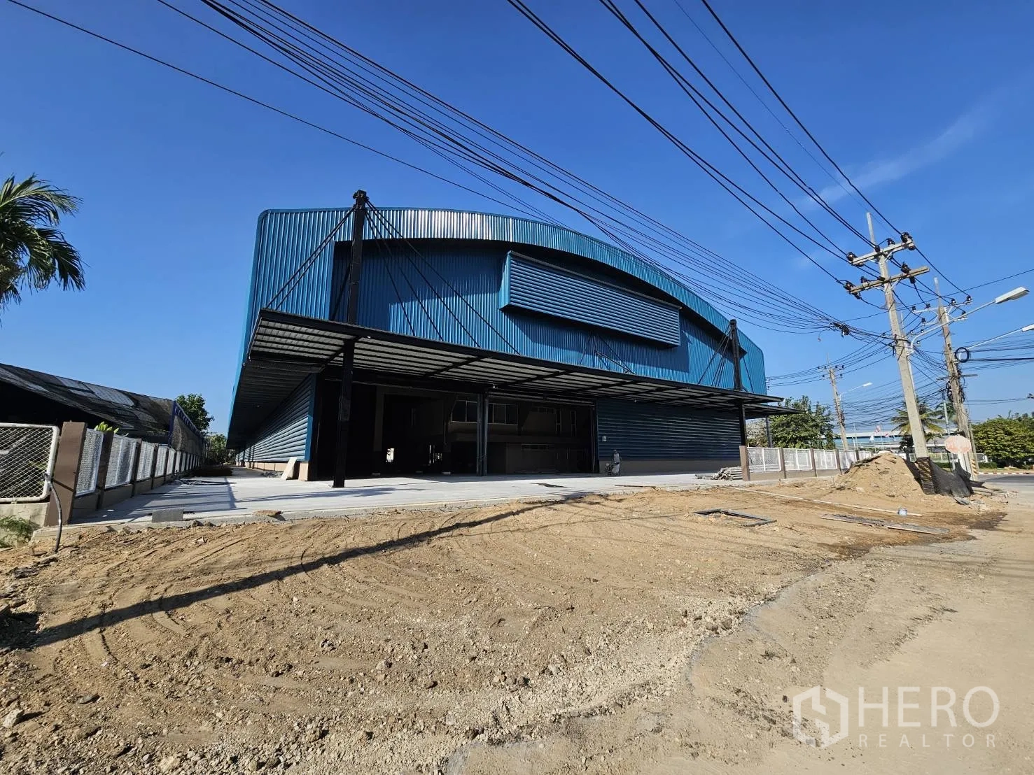 Factory for rent in Chon Buri - Street-side frontage of the blue factory with a large forecourt under preparation.