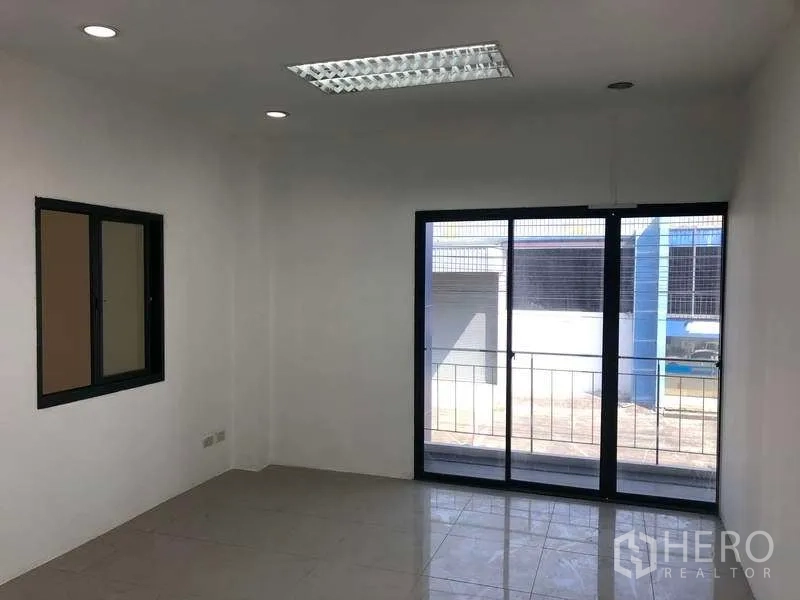 Factory for rent or sale in Samut Prakan - Office room with sliding glass doors opening to a small balcony.