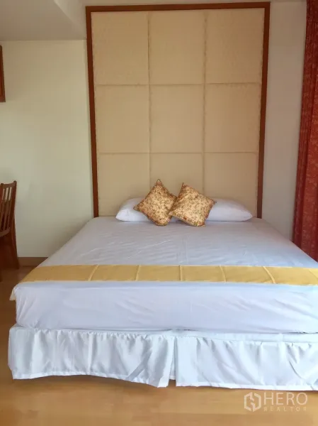 Condominium for rent in Khlong Toei, Bangkok - Bright master bedroom with king bed, padded headboard and light wood flooring.