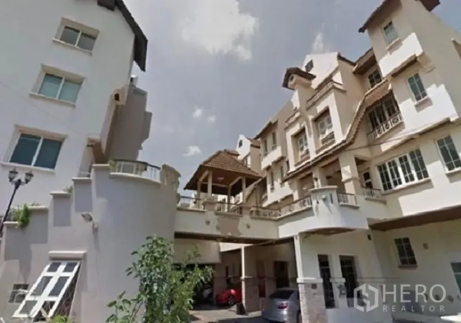 Home Office for rent in Chatuchak, Bangkok - Multi-storey home office facade with balconies, gabled roofs and a covered carport under a bright sky.