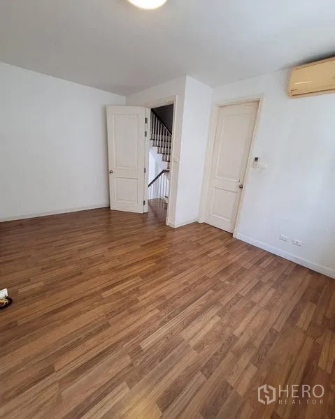 Townhouse for sale in Bang Kapi, Bangkok - Second bedroom with wood floor, white doors and air-conditioning.