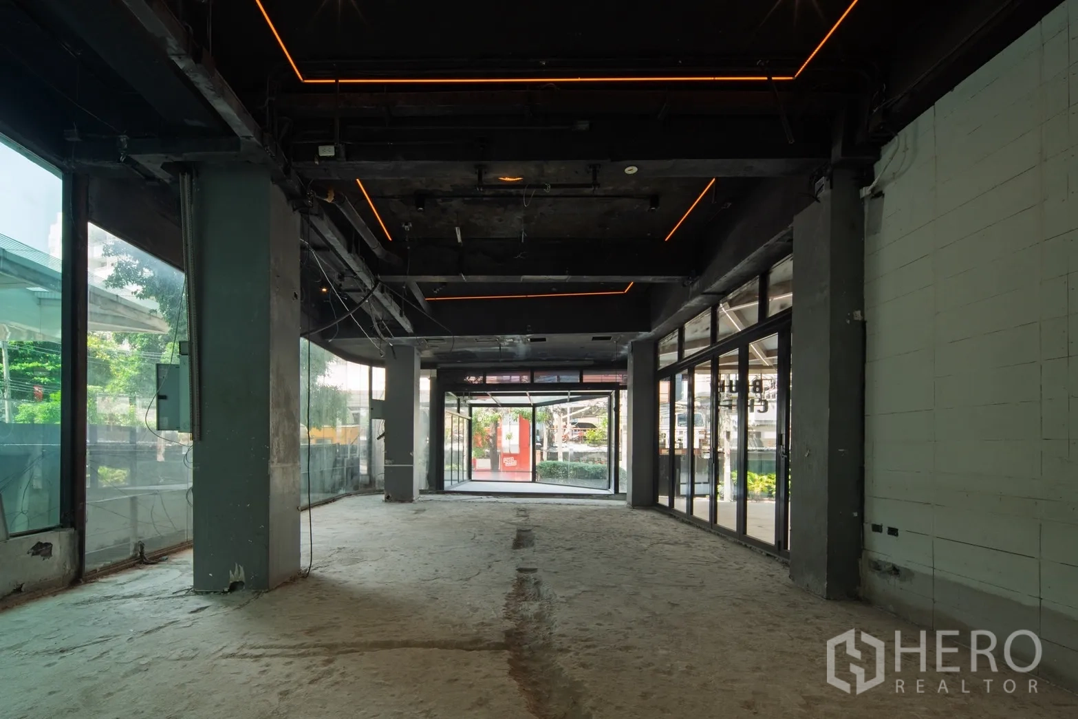 Retail Space for rent in Khlong Toei, Bangkok - Long open-plan retail floor with exposed black ceiling and LED strips, lined with full-height glazing.