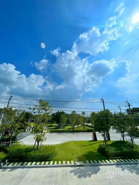 联排别墅 出租在Bang Phli, Samut Prakan - 社区绿化景观，草坪、行道树与宽阔道路。