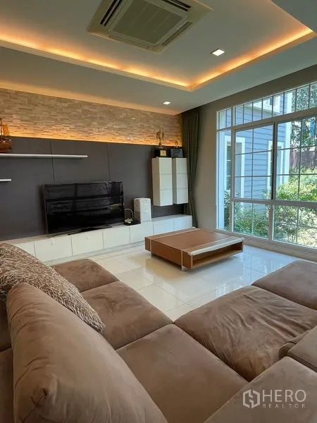 Detached House for rent in Bang Phli, Samut Prakan - Living room TV wall with backlit feature and sectional sofa.