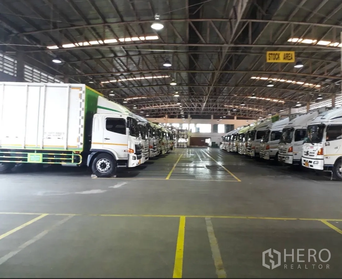 Factory for rent in Uthai, Phra Nakhon Si Ayutthaya - Large warehouse with high steel roof and rows of trucks parked in marked bays.