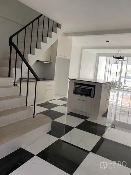 Townhouse for rent or sale in Khlong Toei, Bangkok - Modern kitchen island beside stairs with glass doors leading to the patio