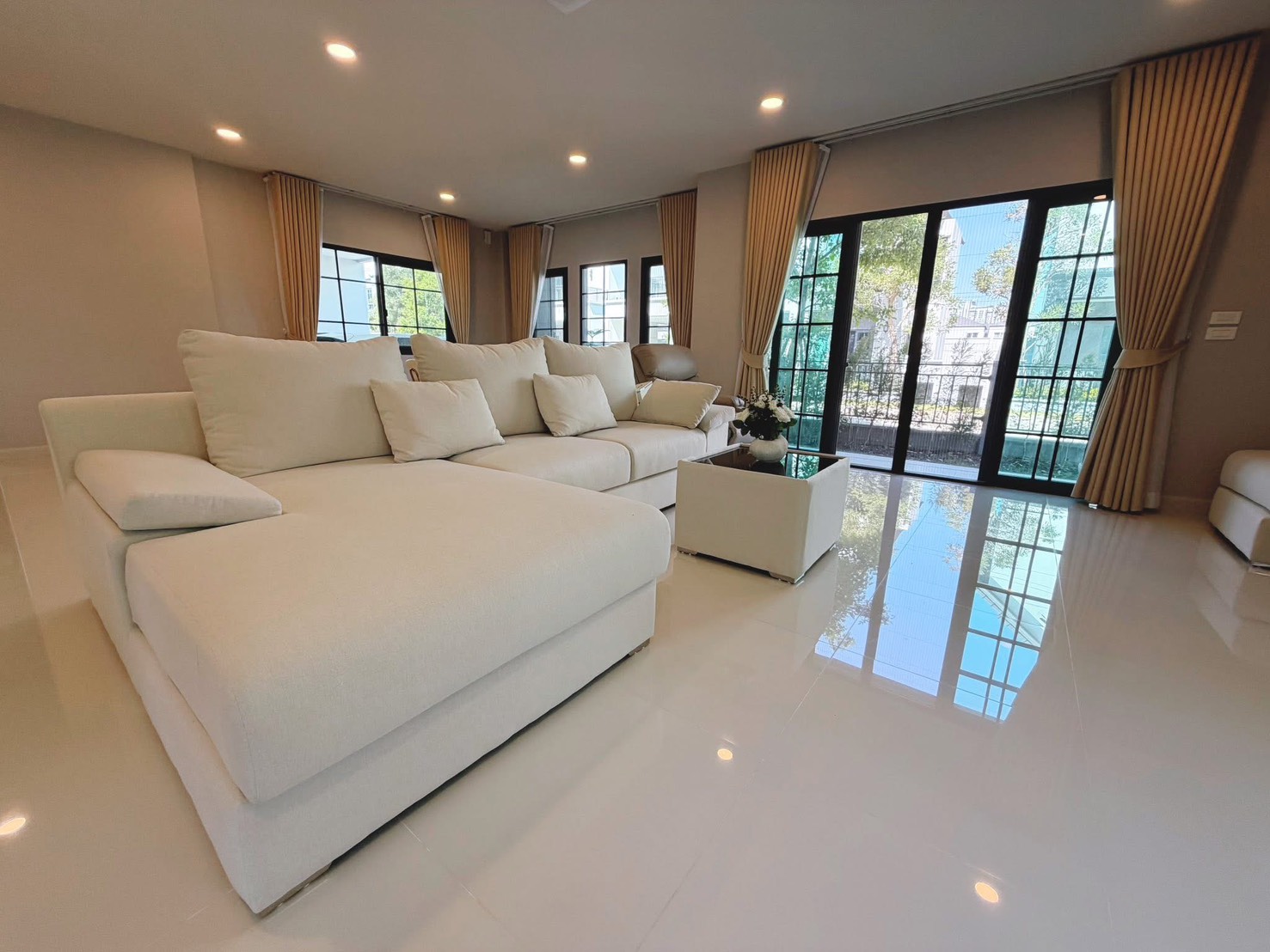 Detached House for rent in Bang Phli, Samut Prakan - Open-plan living space with L-shaped sofa, glossy floors and sliding doors to terrace.