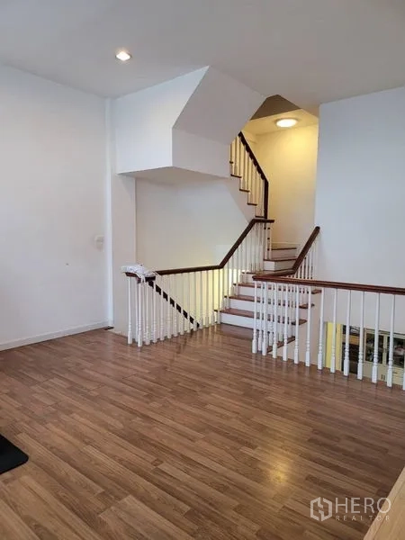 Townhouse for sale in Bang Kapi, Bangkok - Landing area showing L-shaped staircase, white balustrade and wood floors.