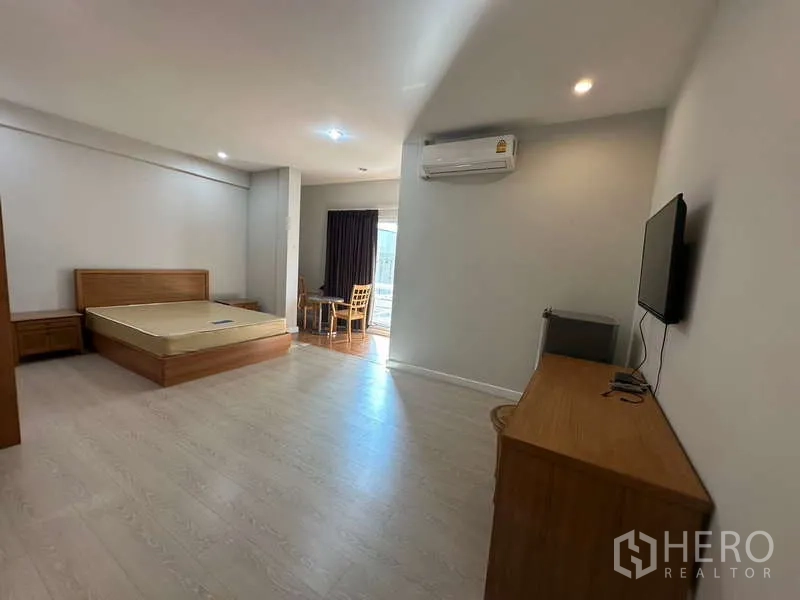 Home Office for rent in Chatuchak, Bangkok - Spacious studio-style room with bed, TV, desk, wood floors and air conditioning.