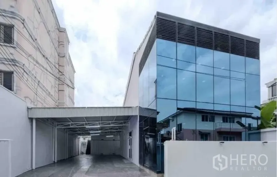 Standalone for rent or sale in Bang Na, Bangkok - Modern standalone building in Bang Na with reflective glass façade and a covered driveway.