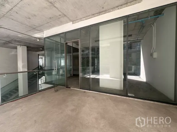 Retail Space for rent - Entrance with full-height sliding glass doors and balcony railing leading to an open-plan retail space near BTS Punnawithi.