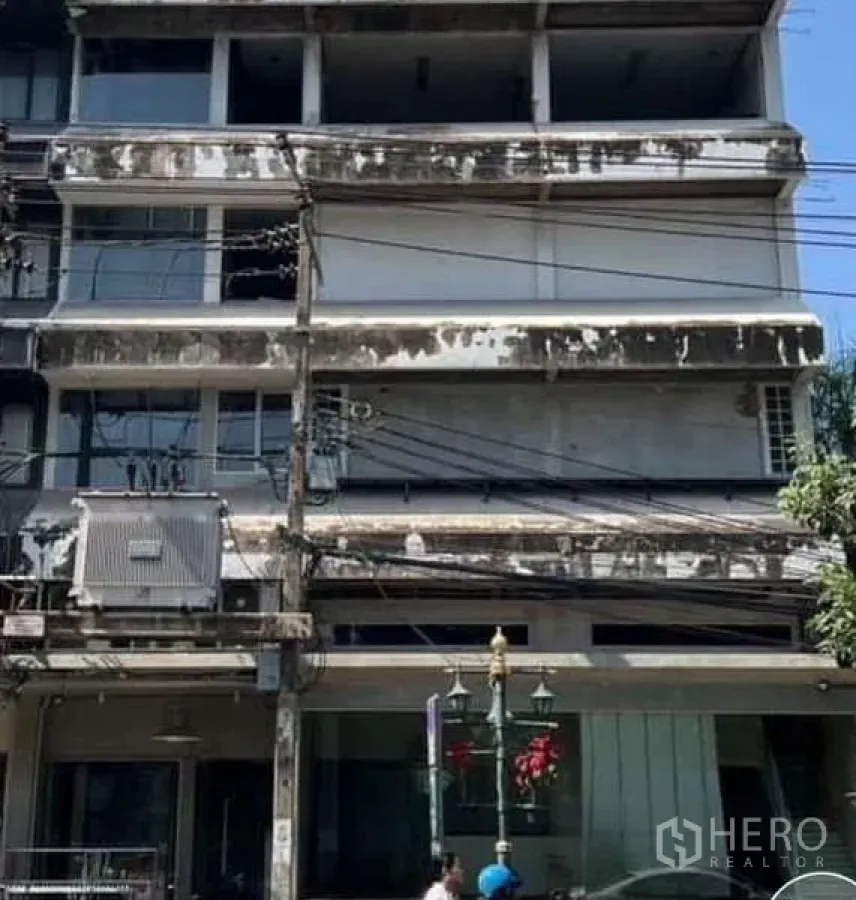 店屋 出租在Watthana, Bangkok - 曼谷多层店屋立面，旧混凝土外墙与街边电缆。