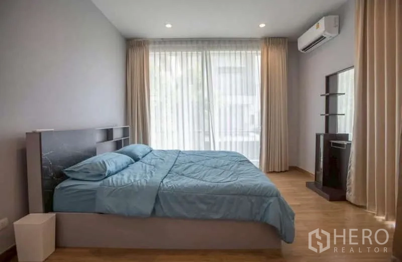 Detached House for rent or sale in Lat Phrao, Bangkok - Primary bedroom with large windows, sheer curtains and wood floors.