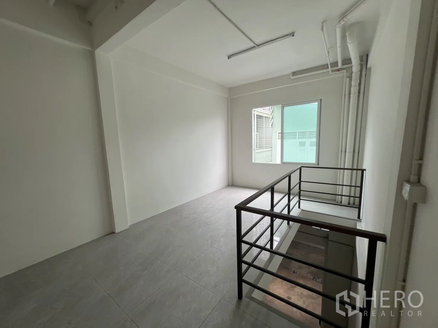 Shophouse for rent in Khlong Toei, Bangkok - Upper landing with railing, windows and visible service pipes.