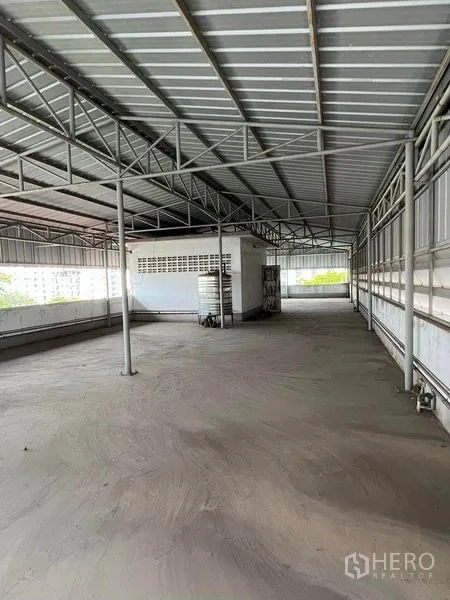 Factory for rent in Bang Na, Bangkok - Covered rooftop storage area with metal truss roof and side ventilation panels.