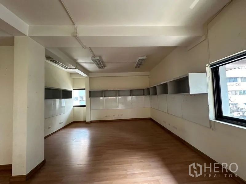 Office Space for rent in Khlong Toei, Bangkok - Spacious corner office area with multiple windows, wooden floors, and storage panels.