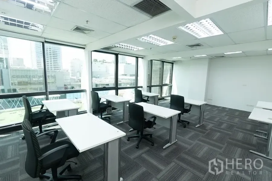 Office Space for rent - Bright open-plan office with white desks, ergonomic chairs and large windows overlooking the city skyline.