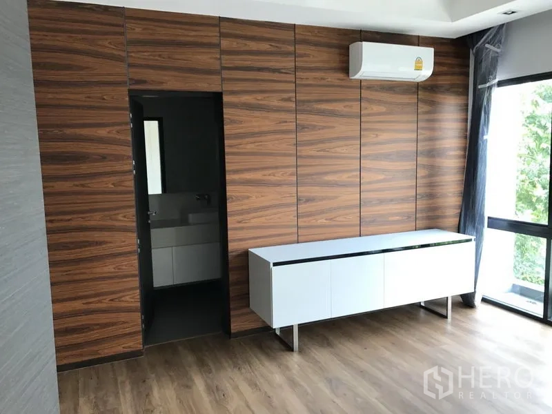 Detached House for rent in Bang Kapi, Bangkok - Secondary bedroom with wood-paneled wardrobe wall, air conditioner and ensuite entrance.