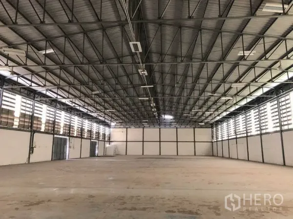 Warehouse for rent in Khlong Luang, Pathum Thani - Open warehouse floor with high metal roof, louvered windows on both sides and reinforced concrete slab.