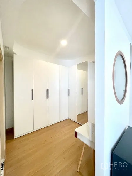 Townhouse for rent in Khlong Toei, Bangkok - Walk-in closet area with full-height white wardrobes and a mirror.