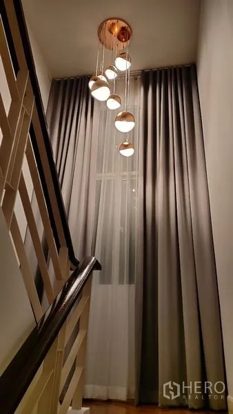 Detached House for rent in Prawet, Bangkok - Stairwell featuring cascading pendant lights and floor-to-ceiling curtains.