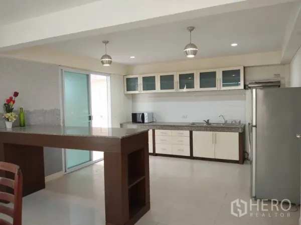 Detached House for rent in Watthana, Bangkok - Open-plan kitchen with breakfast bar, pendant lights and stainless refrigerator.
