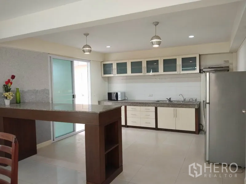 Detached House for rent in Watthana, Bangkok - Open-plan kitchen with breakfast bar, pendant lights and stainless refrigerator.