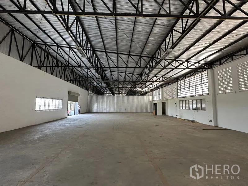Factory for rent in Lam Luk Ka, Pathum Thani - Wide warehouse hall showing roller door entry and metal-clad rear wall.