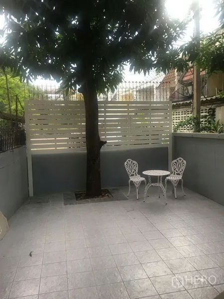 Townhouse for rent in Watthana, Bangkok - Private tiled patio with shade tree and white bistro table and chairs.