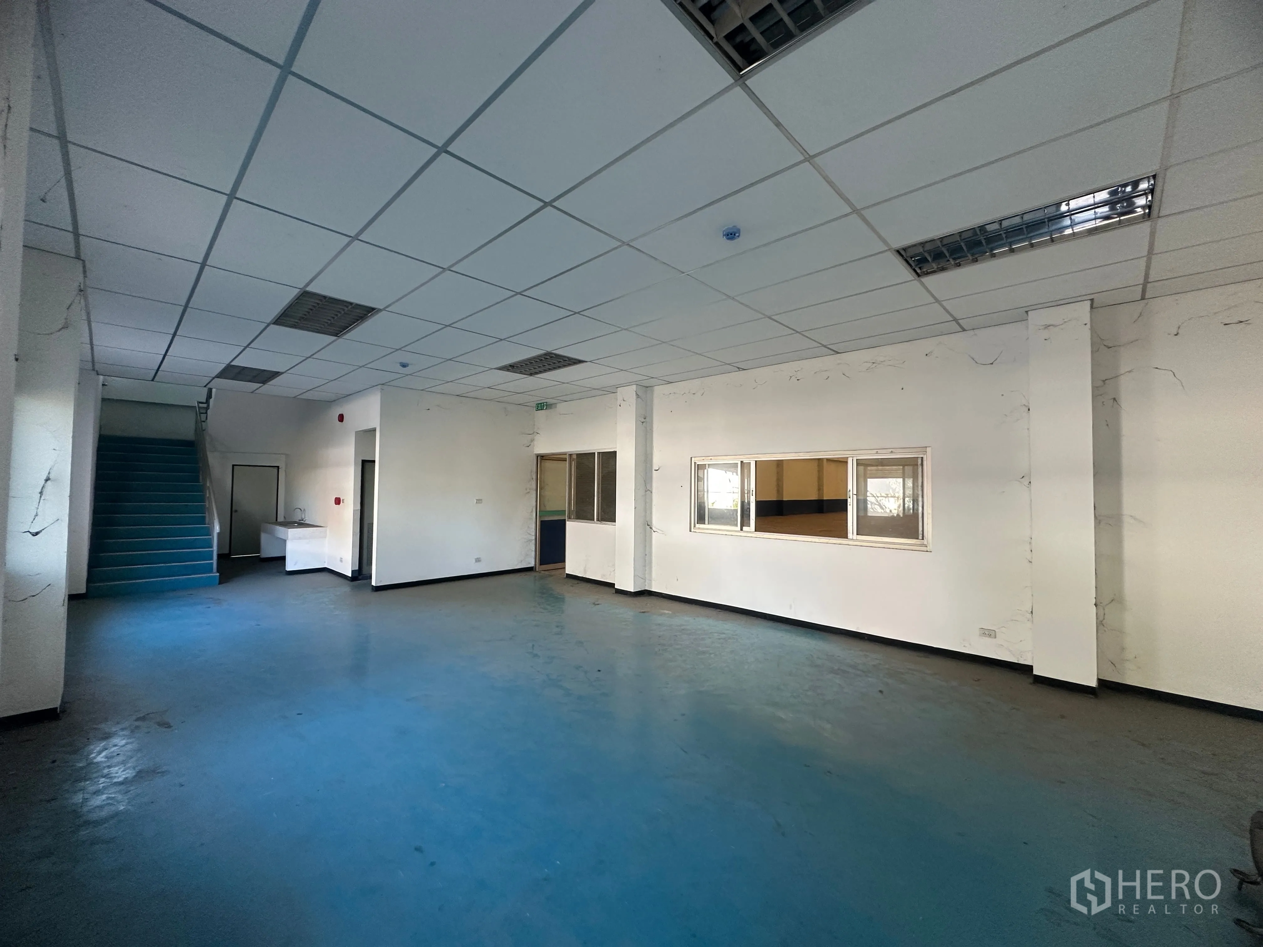 Factory for rent in Bang Pa-in, Phra Nakhon Si Ayutthaya - Ground-floor office area with blue flooring, staircase, and windows to the factory.