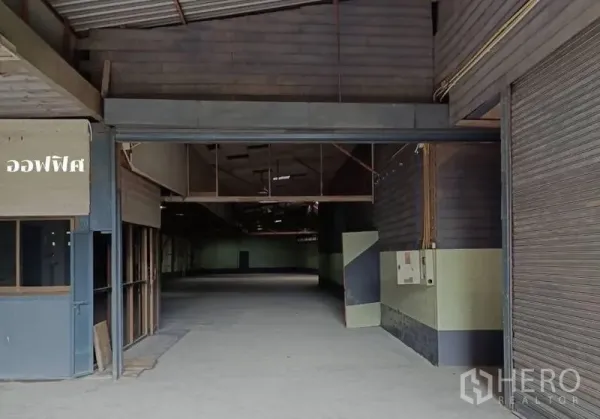 Warehouse for rent in Bang Khen, Bangkok - Front loading area showing roller shutter door and electrical panel at the entry.
