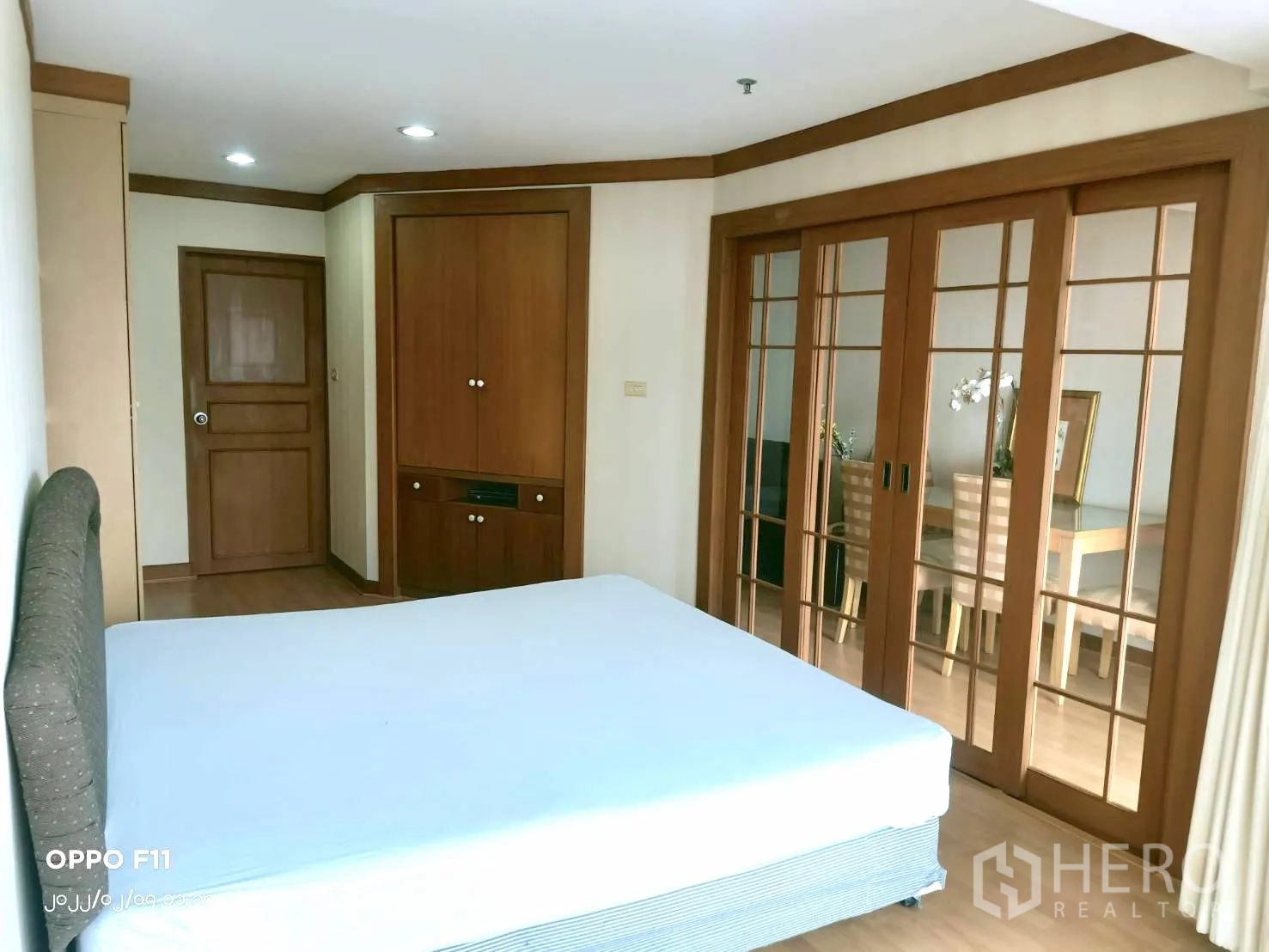 Condominium for rent in Khlong Toei, Bangkok - Bedroom featuring a built-in wardrobe and sliding glass doors opening to the dining area.