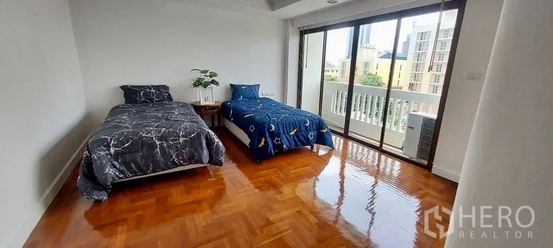 Townhouse for rent in Sathon, Bangkok - Twin bedroom with city-view balcony and floor-to-ceiling sliding glass.