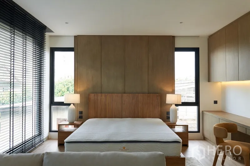 Detached House for rent in Watthana, Bangkok - Primary bedroom with large windows, wood feature wall and built-in desk.