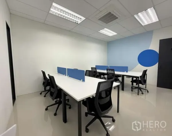 办公空间 出租在Huai Khwang, Bangkok - 明亮的服务式办公室，白色长桌、蓝色隔板与人体工学网椅。