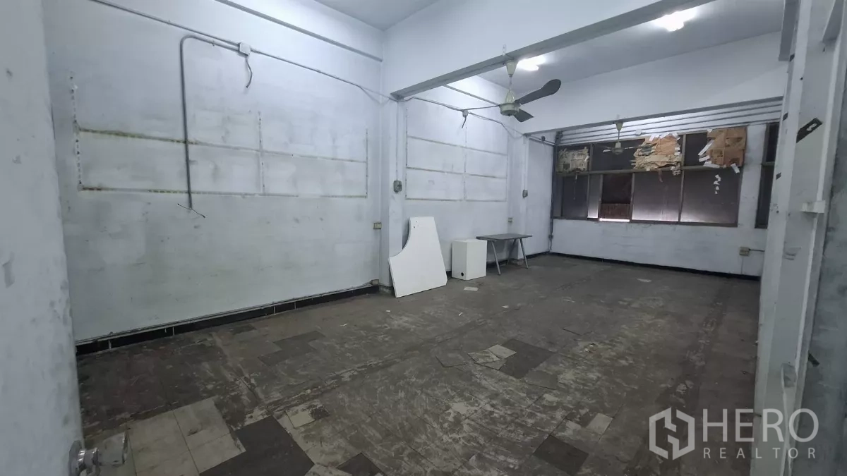 Shophouse for rent in Watthana, Bangkok - Upper-floor room with ceiling fans and worn tile flooring, ready to renovate.