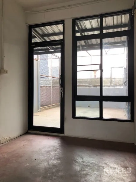 Shophouse for rent - Interior room opening to the terrace via black-framed glass door and windows.
