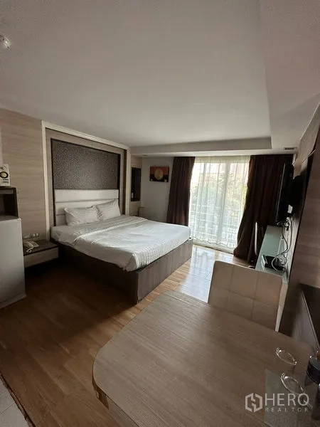 房间 出租在Khlong Toei, Bangkok - 配家具的开间卧室，含床、电视与通向阳台的推拉门。