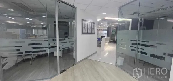 Office Space for rent in Bang Rak, Bangkok - Entrance corridor with curved glass offices on both sides and light wood flooring in a Bangkok CBD building.