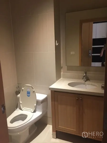 Condominium for rent - Guest bathroom with vanity, mirror, and toilet in warm neutral tiles.