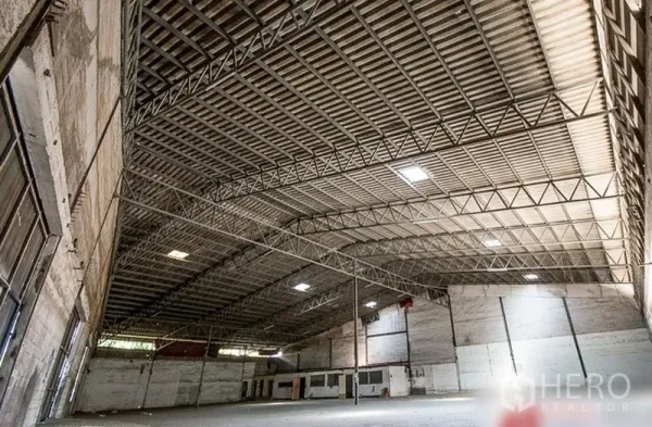 Warehouse for rent in Bang Phli, Samut Prakan - Spacious warehouse interior featuring a high clear-span steel truss roof with skylight panels.