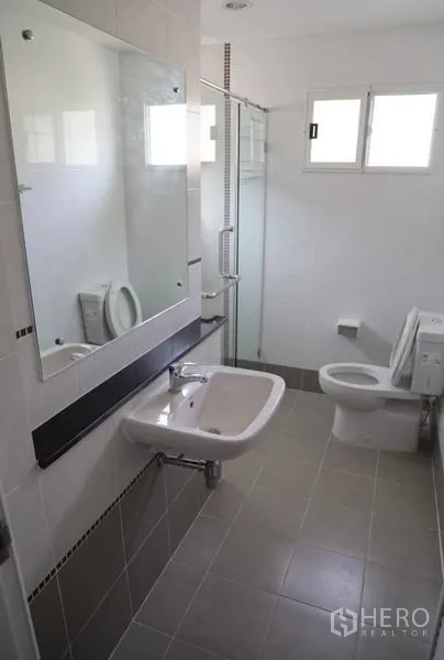 Detached House for rent in Suan Luang, Bangkok - Clean bathroom with glass shower enclosure, toilet, sink and large mirror.