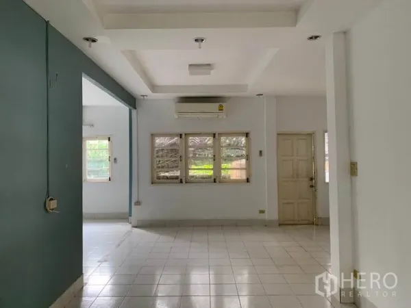 Detached House for rent in Khlong Toei, Bangkok - Open-plan living room with white floor tiles, recessed ceiling and air conditioner.