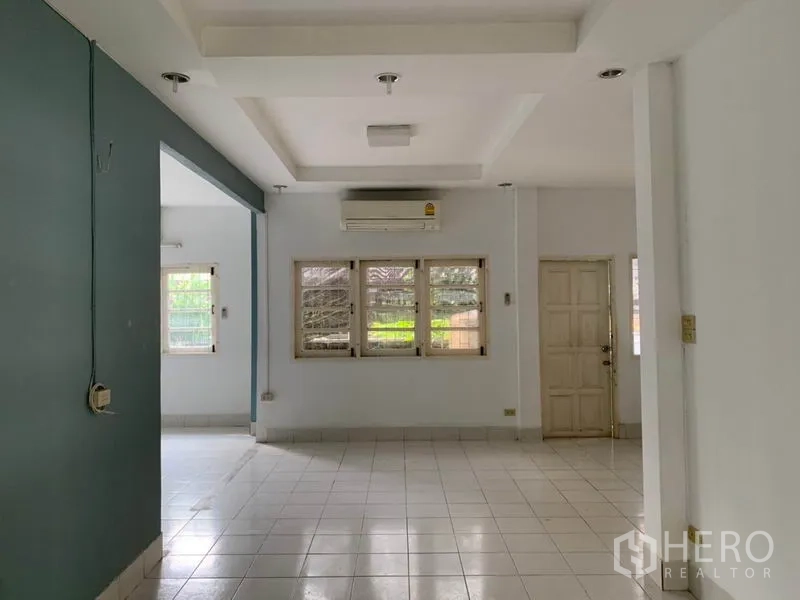 Detached House for rent in Khlong Toei, Bangkok - Open-plan living room with white floor tiles, recessed ceiling and air conditioner.