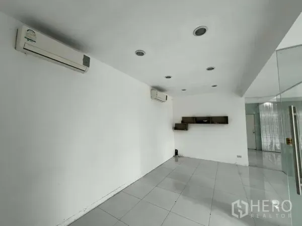 Showroom for rent - Air-conditioned office room with white tiles and wall shelves.